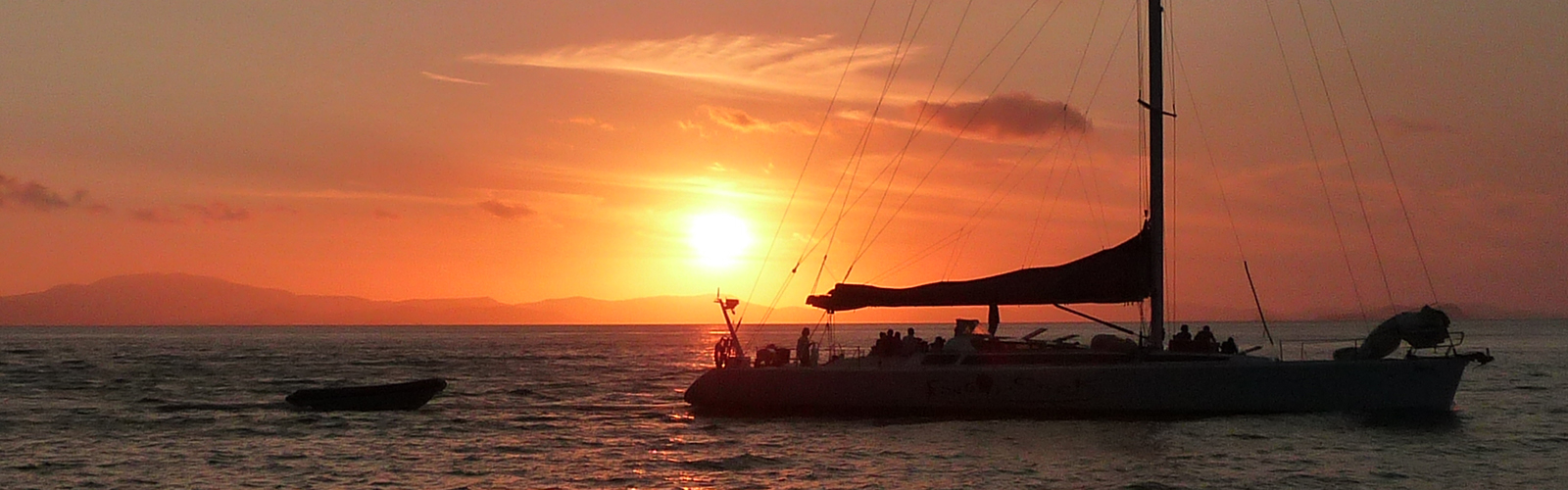 Sunset on the water with a sailboat in the foreground.